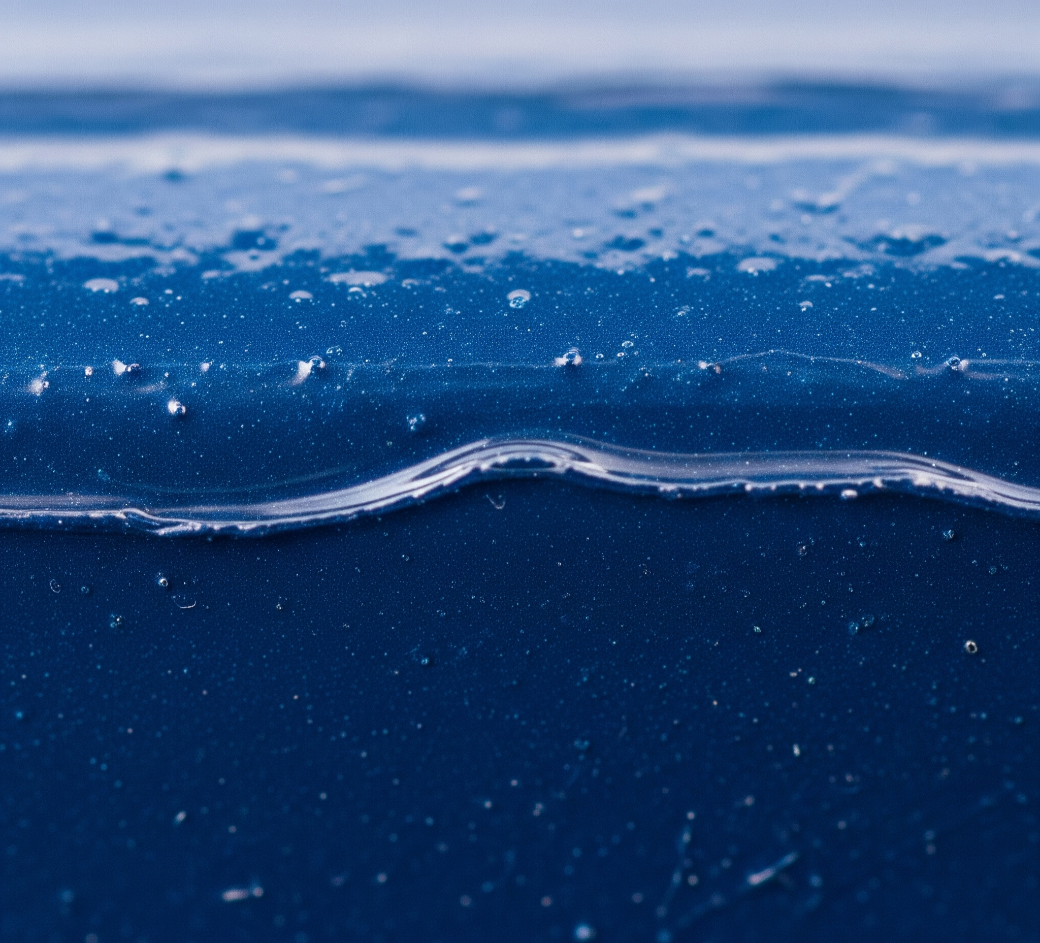 Vista macro ultra-realista de uma superfície metálica industrial pintada com uma camada de tinta azul escura perfeitamente aplicada e brilhante, mostrando pequenas bolhas de ar e uma fina camada translúcida de resina protetora na superfície.