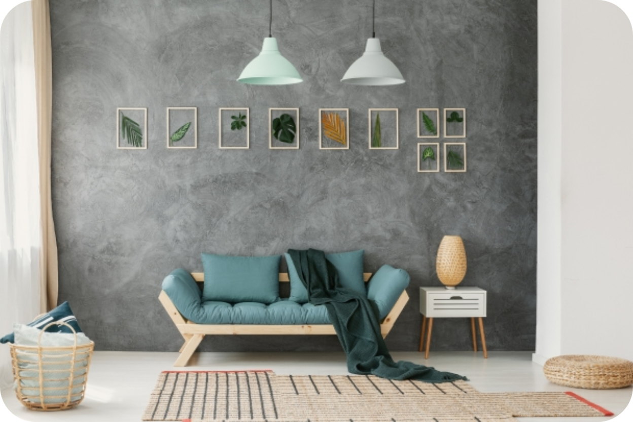 Sala com parede de efeito cimento queimado cinza, sofá de madeira e almofadas azuis, e galeria de quadros de folhas.
