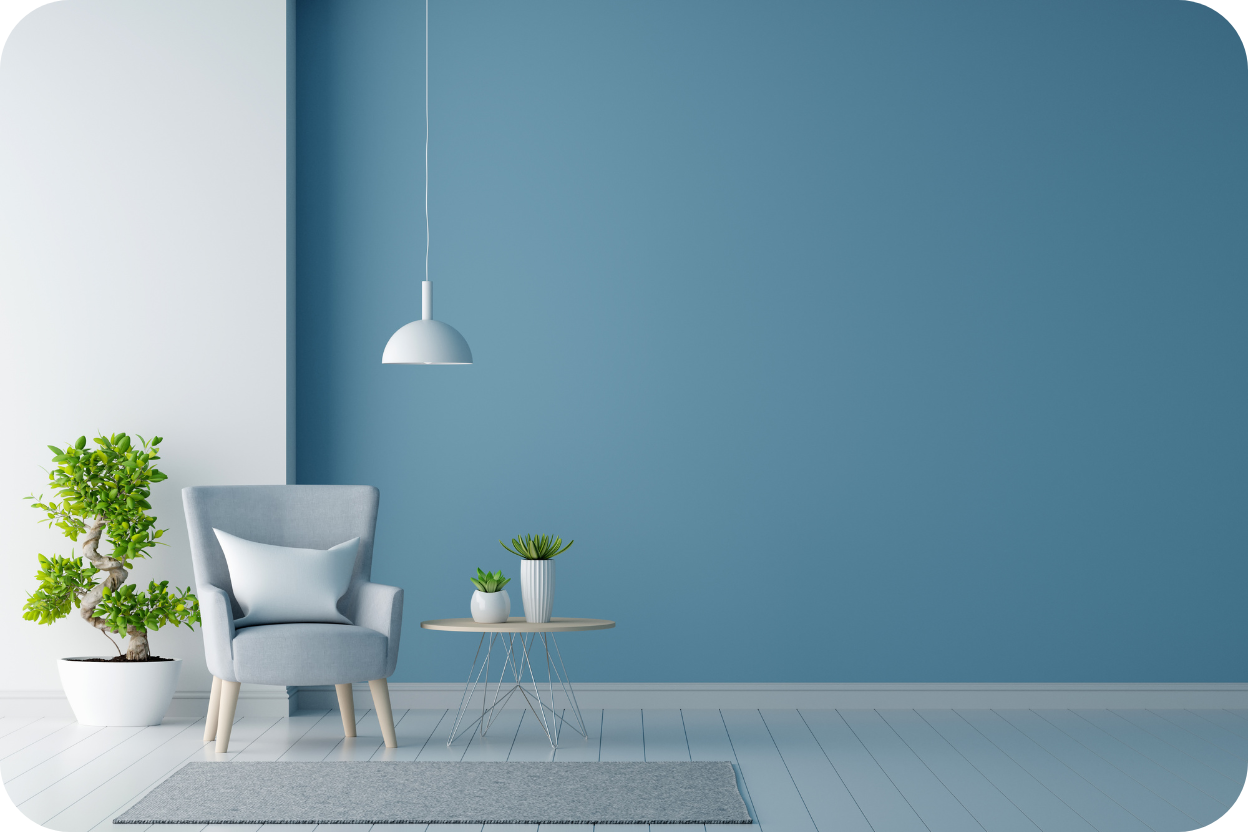 Parede azul pastel em ambiente minimalista com poltrona cinza, luminária pendente branca e mesa lateral redonda.